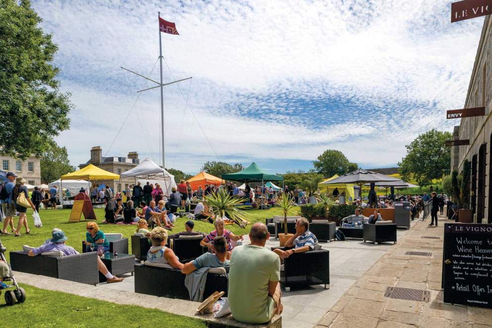 People sitting outside at the Good Food Market in Royal William Yard, Plymouth